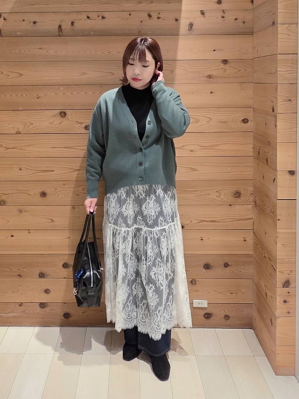 ブラック系のボストンバッグ、ブルー系のデニムパンツ、ブラック系のステンカラーコートを着用したレディースの秋コーディネートの4枚目の写真