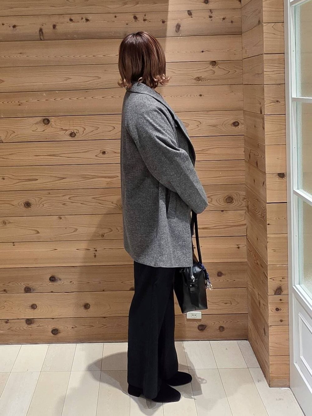 ブラック系のボストンバッグ、グレー系のチェスターコート、ブラック系のその他パンツを着用したレディースの冬コーディネートの2枚目の写真