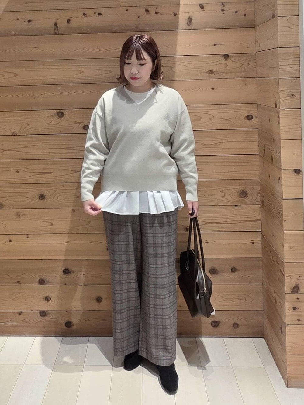 ブラウン系のボストンバッグ、ブラック系のダウンジャケット/コート、ベージュ系のスウェットを着用したレディースの冬コーディネートの4枚目の写真