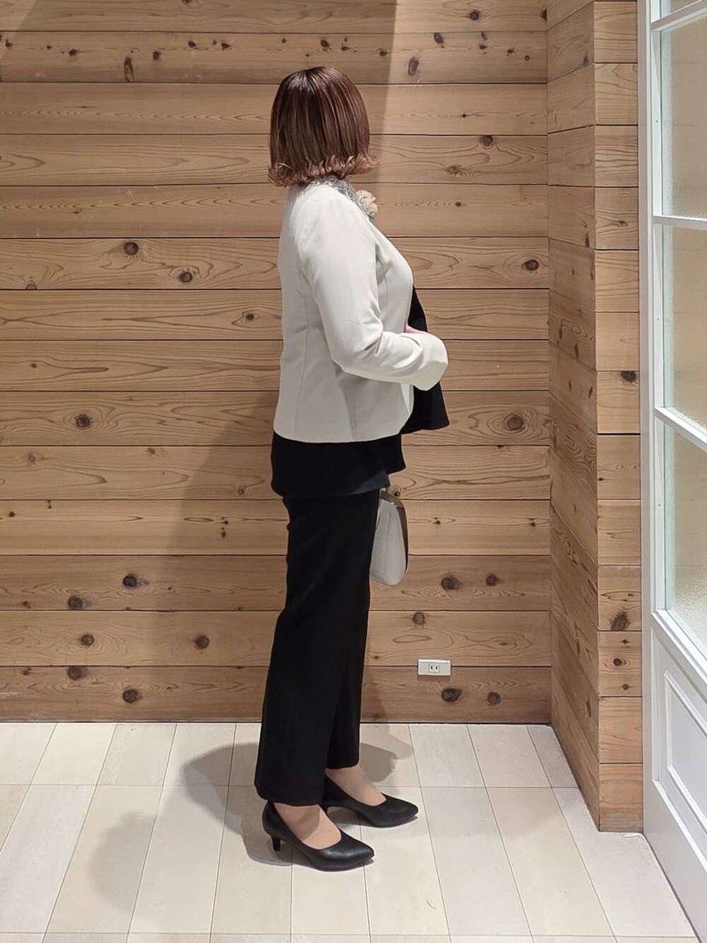 ホワイト系のショルダーバッグ、ブラック系のパンプス、ベージュ系のセットアップを着用したレディースの冬コーディネートの2枚目の写真