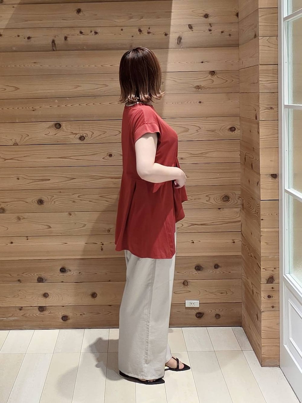 ベージュ系のその他パンツ、レッド系のTシャツ/カットソー、ブラック系のクラッチバッグを着用したレディースの夏コーディネートの2枚目の写真