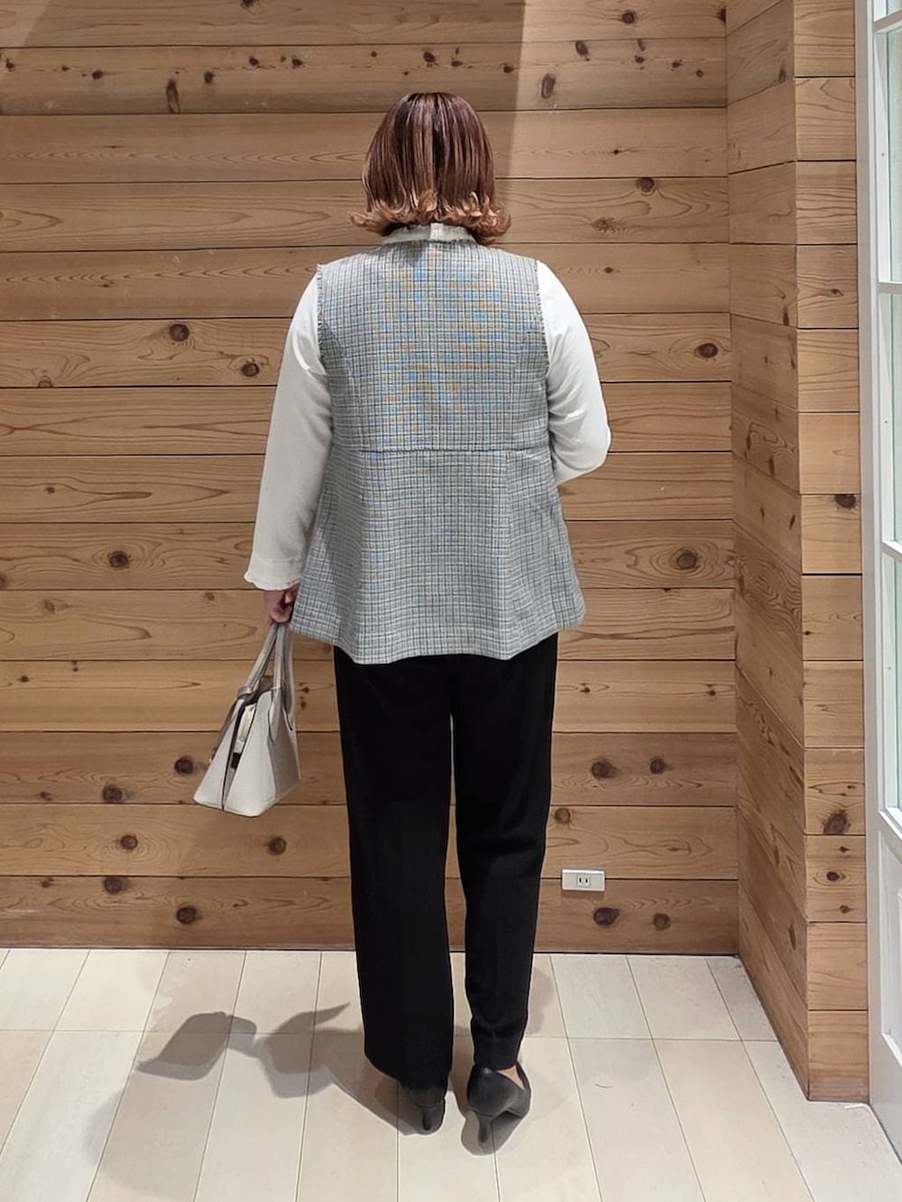 ホワイト系のショルダーバッグ、ブラック系のパンプス、ブラック系のセットアップを着用したレディースの冬コーディネートの3枚目の写真