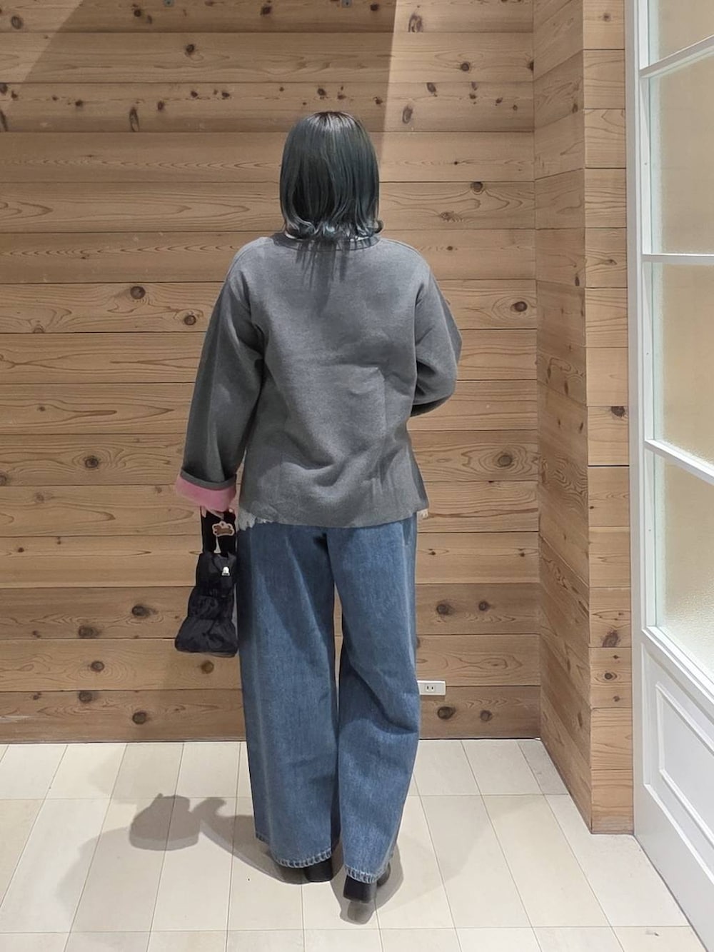 ブルー系のデニムパンツ、ホワイト系のTシャツ/カットソー、ブラック系のトートバッグを着用したレディースの秋コーディネートの3枚目の写真