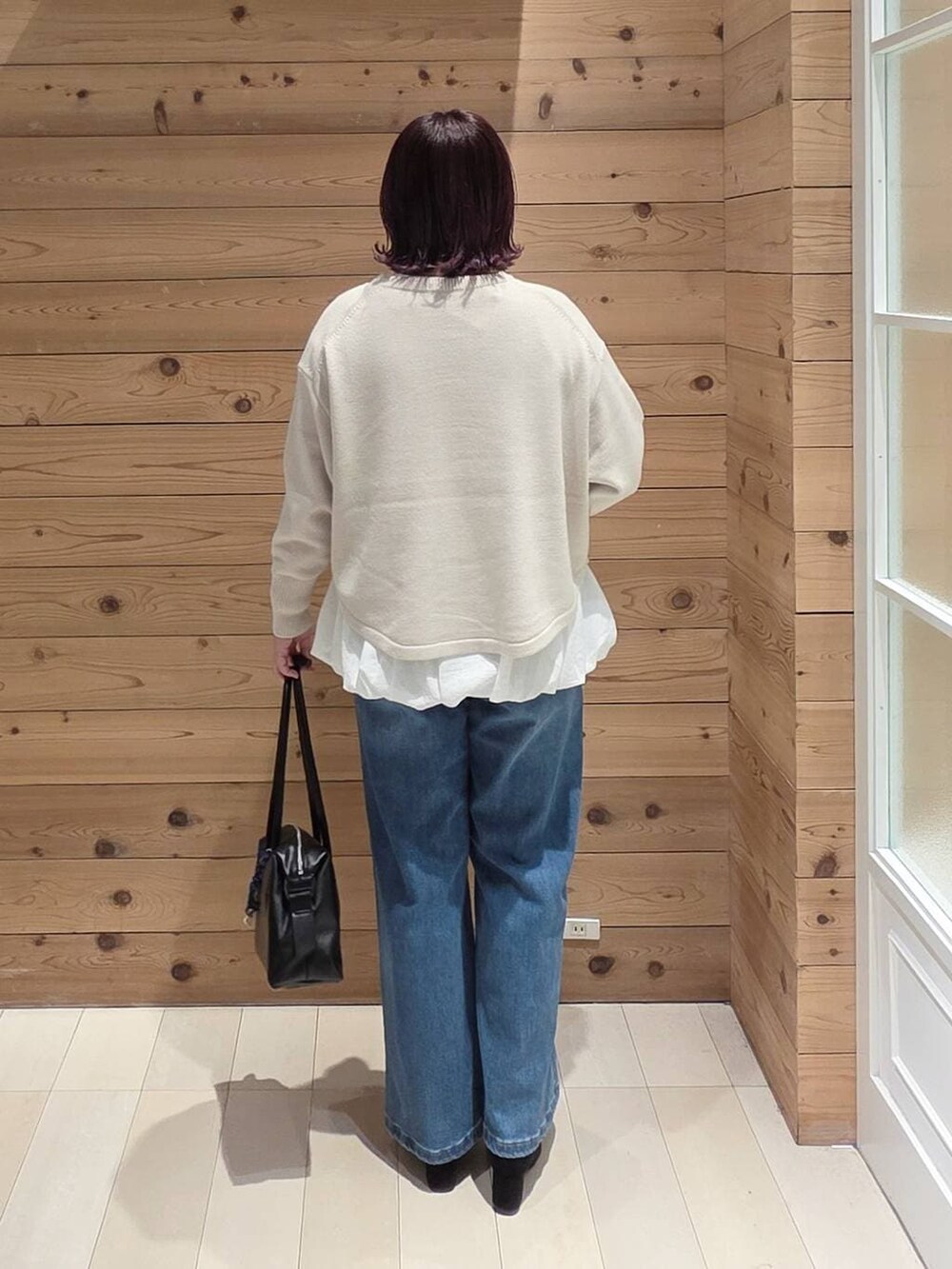 ホワイト系のマウンテンパーカー、ベージュ系のニット/セーター、ブラック系のボストンバッグを着用したレディースの冬コーディネートの3枚目の写真