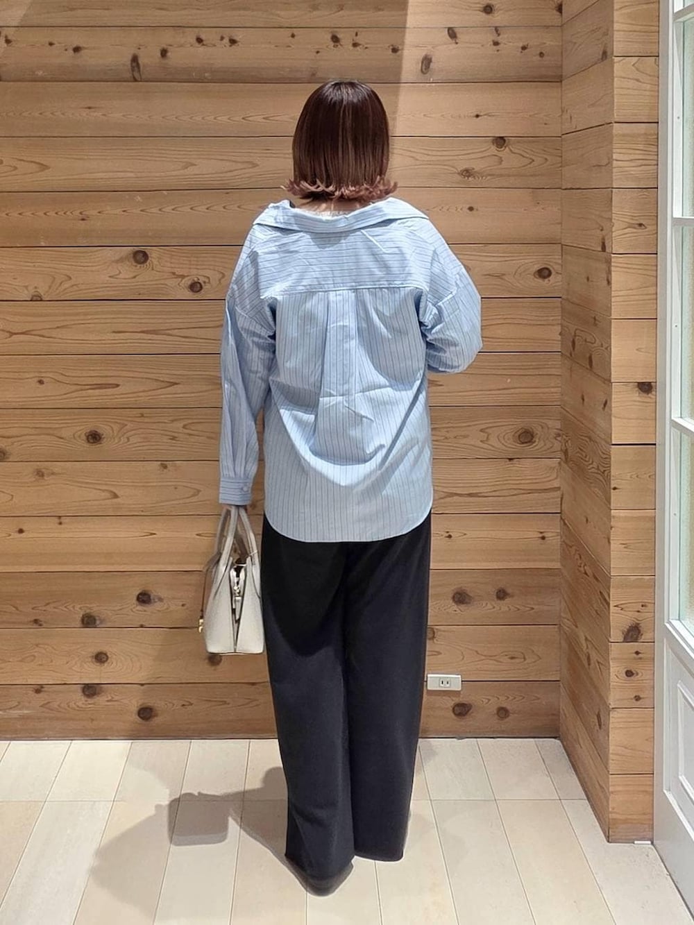 ブラック系のパンプス、ホワイト系のショルダーバッグ、ブルー系のシャツ/ブラウスを着用したレディースの春コーディネートの3枚目の写真