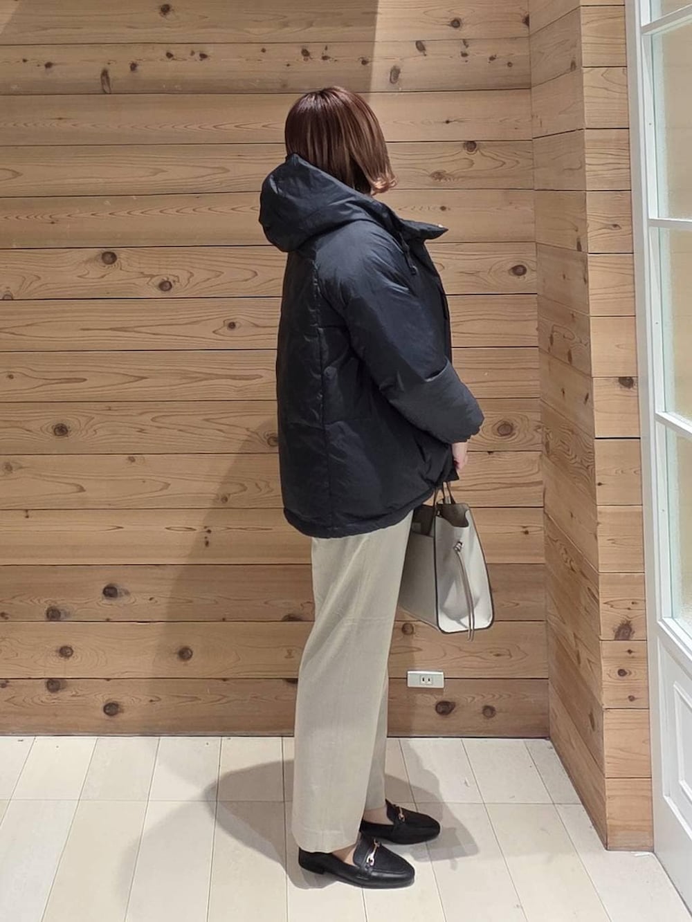 ブラック系のローファー、ホワイト系のショルダーバッグ、ブラック系のダウンジャケット/コートを着用したレディースの冬コーディネートの2枚目の写真