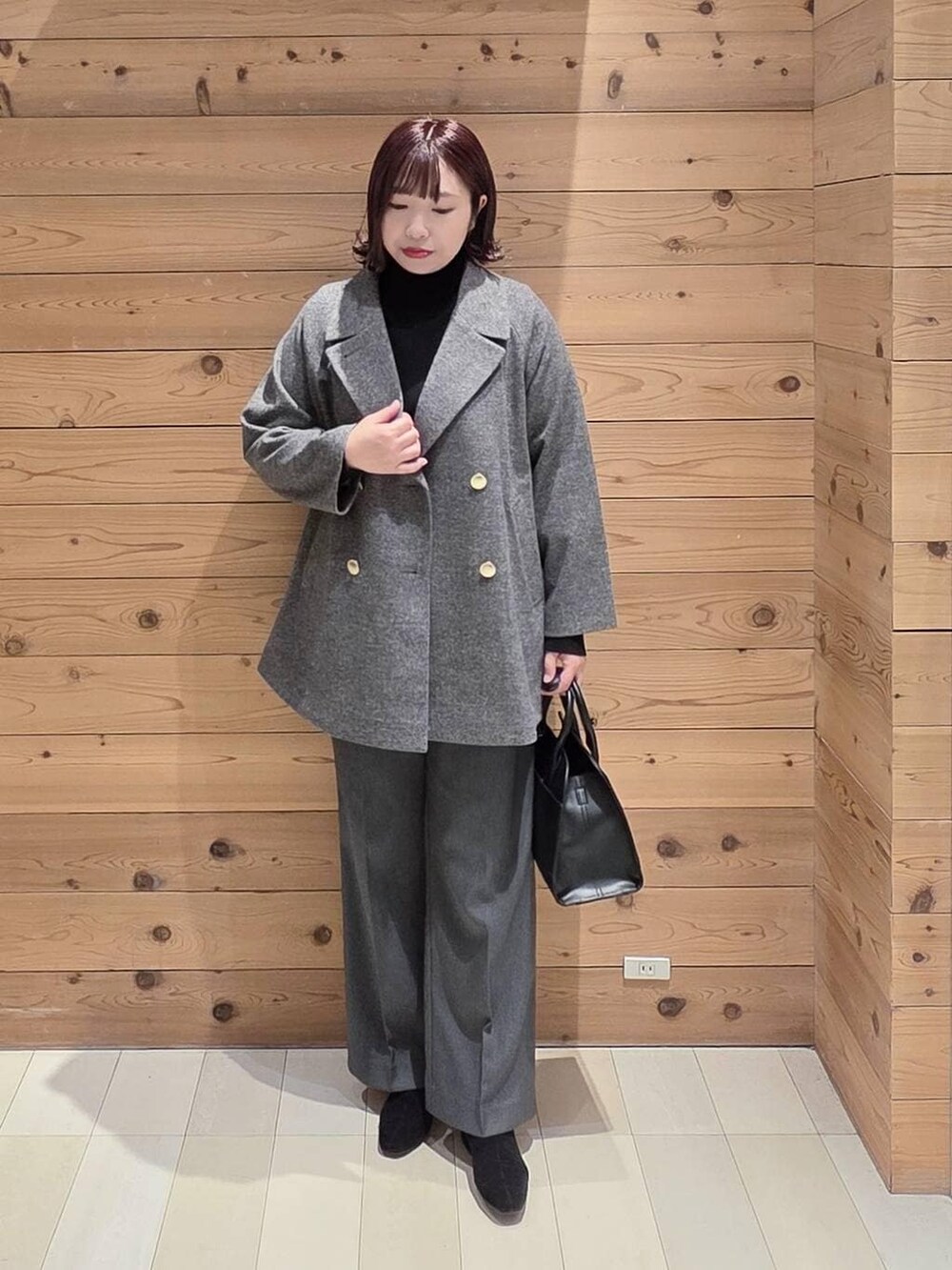 グレー系のチェスターコート、グレー系のその他パンツ、ブラック系のショルダーバッグを着用したレディースの冬コーディネートの4枚目の写真