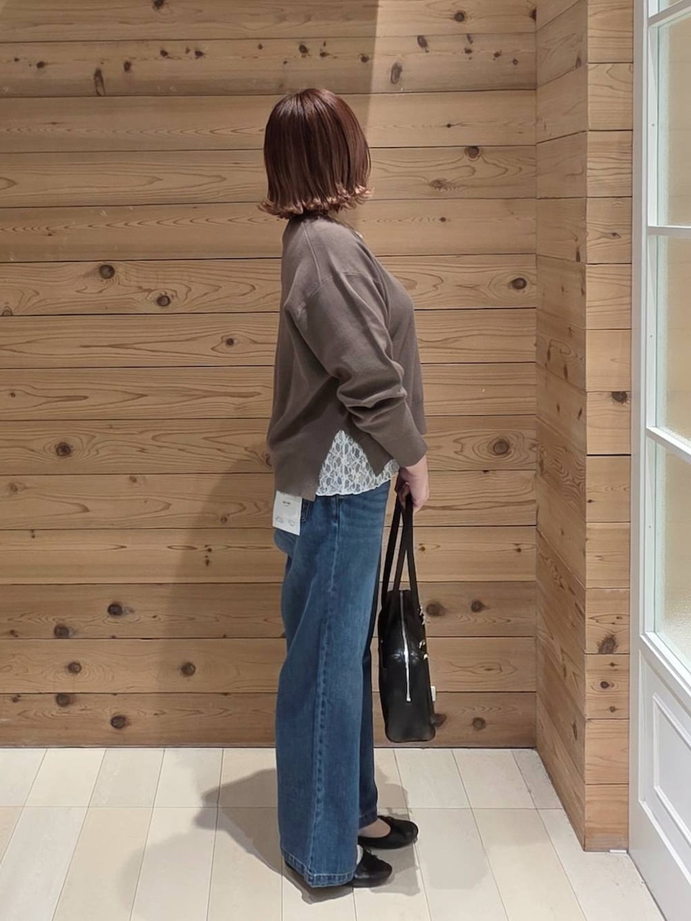 ブラック系のバレエシューズ、ブルー系のデニムパンツ、ブラウン系のニット/セーターを着用したレディースの春コーディネートの2枚目の写真