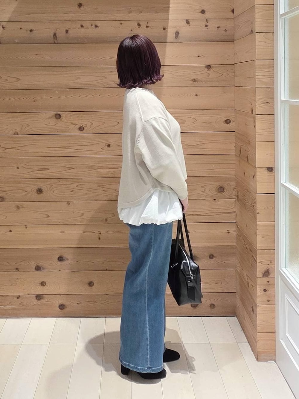 ホワイト系のマウンテンパーカー、ベージュ系のニット/セーター、ブラック系のボストンバッグを着用したレディースの冬コーディネートの2枚目の写真