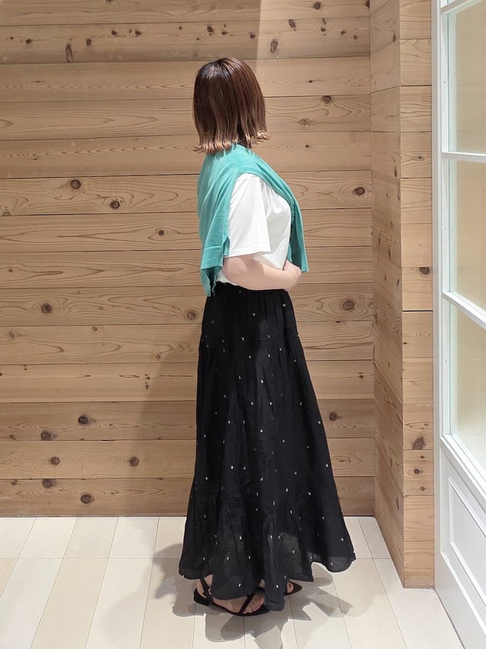 ブラック系のスカート、ホワイト系のTシャツ/カットソー、グリーン系のカーディガン/ボレロを着用したレディースの夏コーディネートの2枚目の写真