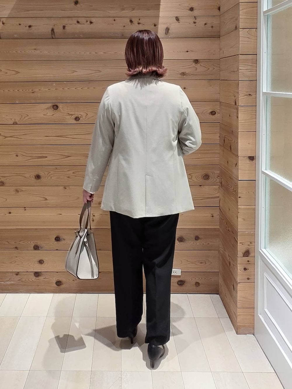 ホワイト系のショルダーバッグ、ブラック系のパンプス、ベージュ系のテーラードジャケットを着用したレディースの冬コーディネートの3枚目の写真