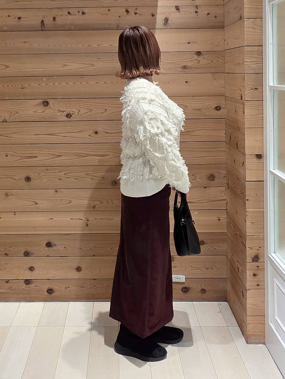 ブラック系のショルダーバッグ、ブラウン系のチェスターコート、レッド系のスカートを着用したレディースの冬コーディネートの2枚目の写真