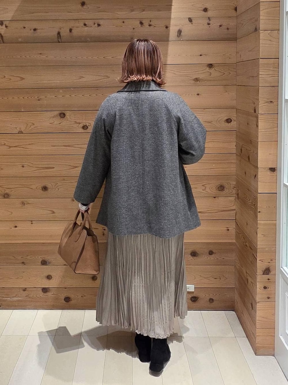 グレー系のチェスターコート、ベージュ系のショルダーバッグ、ホワイト系のTシャツ/カットソーを着用したレディースの冬コーディネートの3枚目の写真