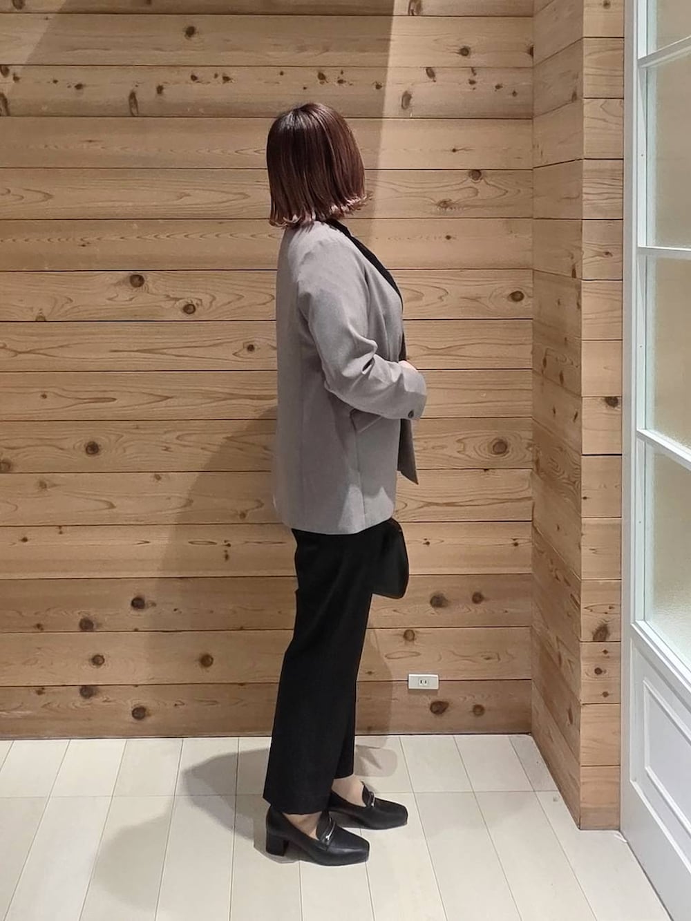 ブラック系のローファー、ブラック系のショルダーバッグ、ブラック系のスラックスを着用したレディースの冬コーディネートの2枚目の写真