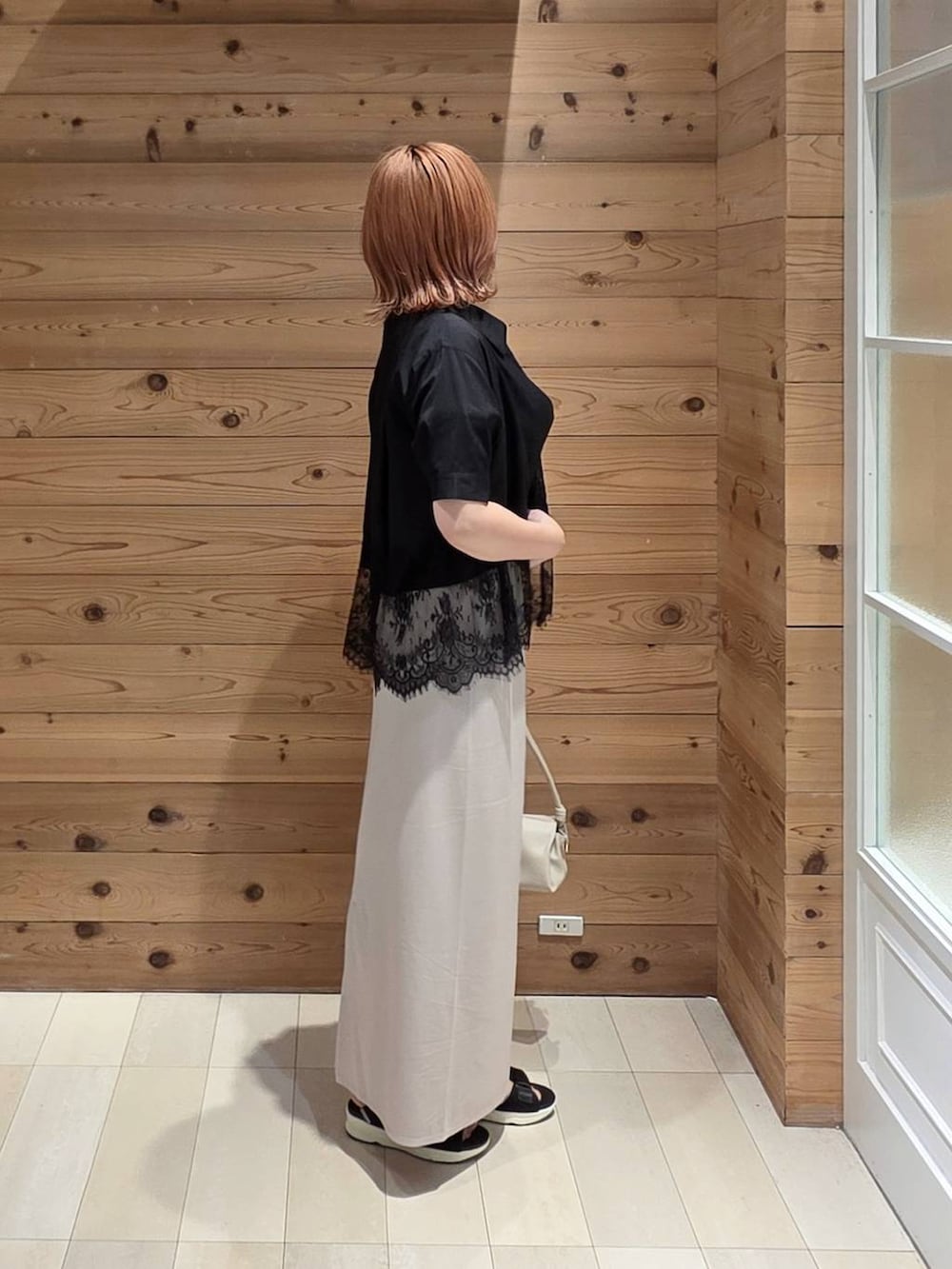 ホワイト系のスカート、ベージュ系のショルダーバッグ、ブラック系のサンダルを着用したレディースの夏コーディネートの2枚目の写真