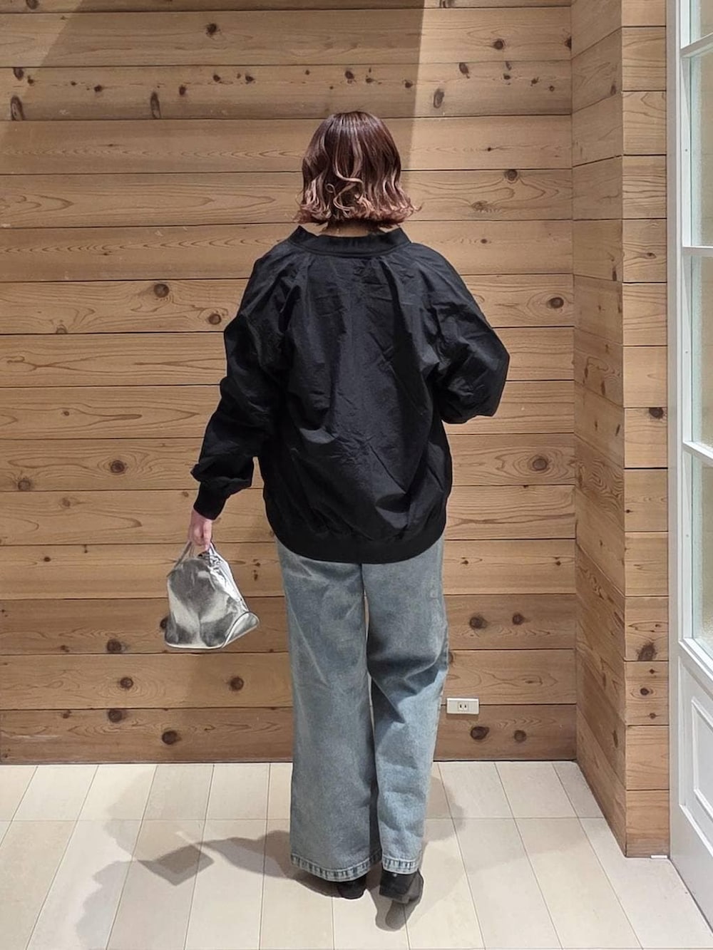 ブラック系のローファー、シルバー系のショルダーバッグ、ブルー系のデニムパンツを着用したレディースの春コーディネートの3枚目の写真