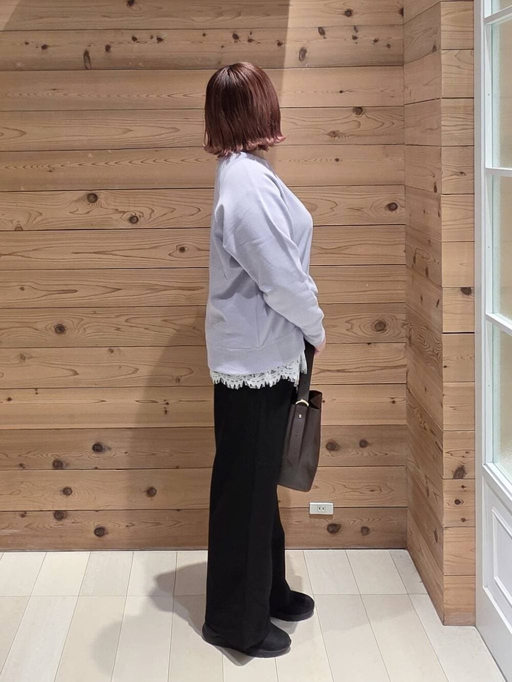 ブラウン系のショルダーバッグ、ブルー系のダウンジャケット/コート、ブラック系のブーツを着用したレディースの冬コーディネートの2枚目の写真