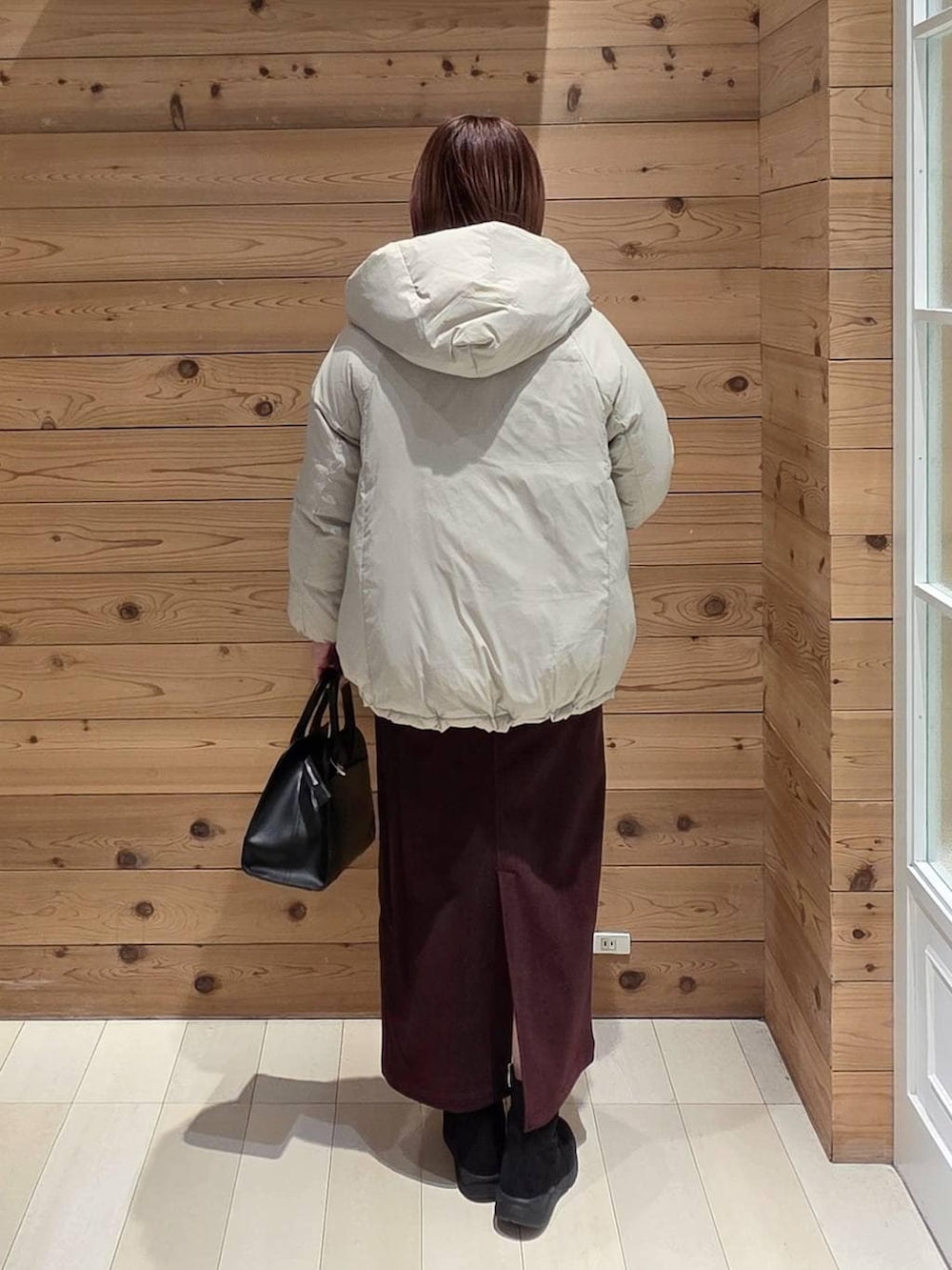 ベージュ系のダウンジャケット/コート、レッド系のスカート、ブラック系のブーツを着用したレディースの冬コーディネートの3枚目の写真