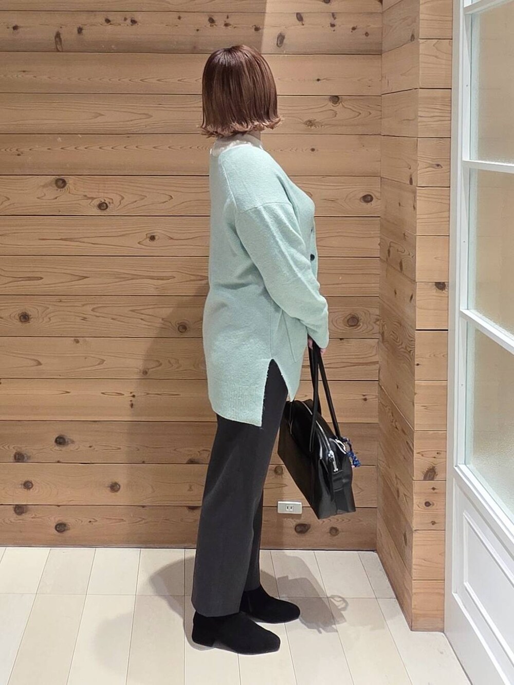 ブラック系のボストンバッグ、ブラック系のダウンジャケット/コート、ホワイト系のニット/セーターを着用したレディースの秋コーディネートの2枚目の写真