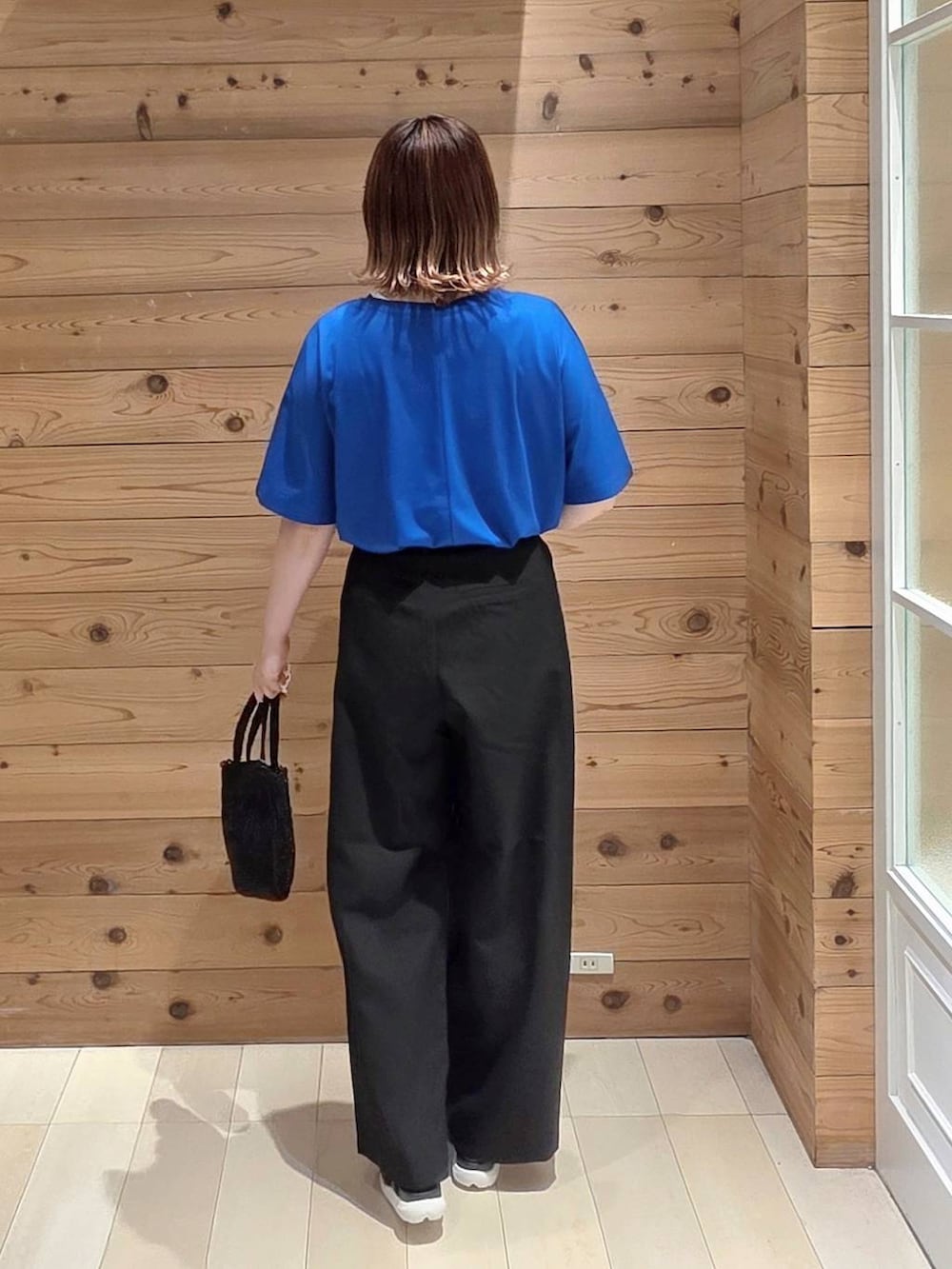 ブラック系のその他パンツ、ブルー系のTシャツ/カットソー、ブラック系のクラッチバッグを着用したレディースの夏コーディネートの3枚目の写真