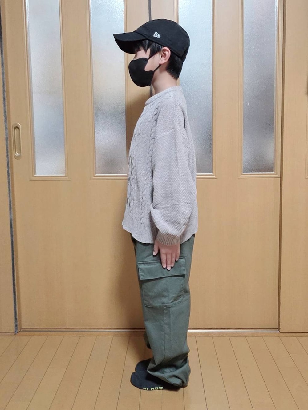 グリーン系のカーゴパンツ、ベージュ系のニット/セーターを着用したキッズの冬コーディネートの2枚目の写真