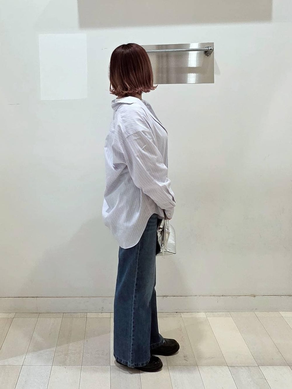 シルバー系のショルダーバッグ、ブラック系のローファー、ブルー系のデニムパンツを着用したレディースの春コーディネートの2枚目の写真