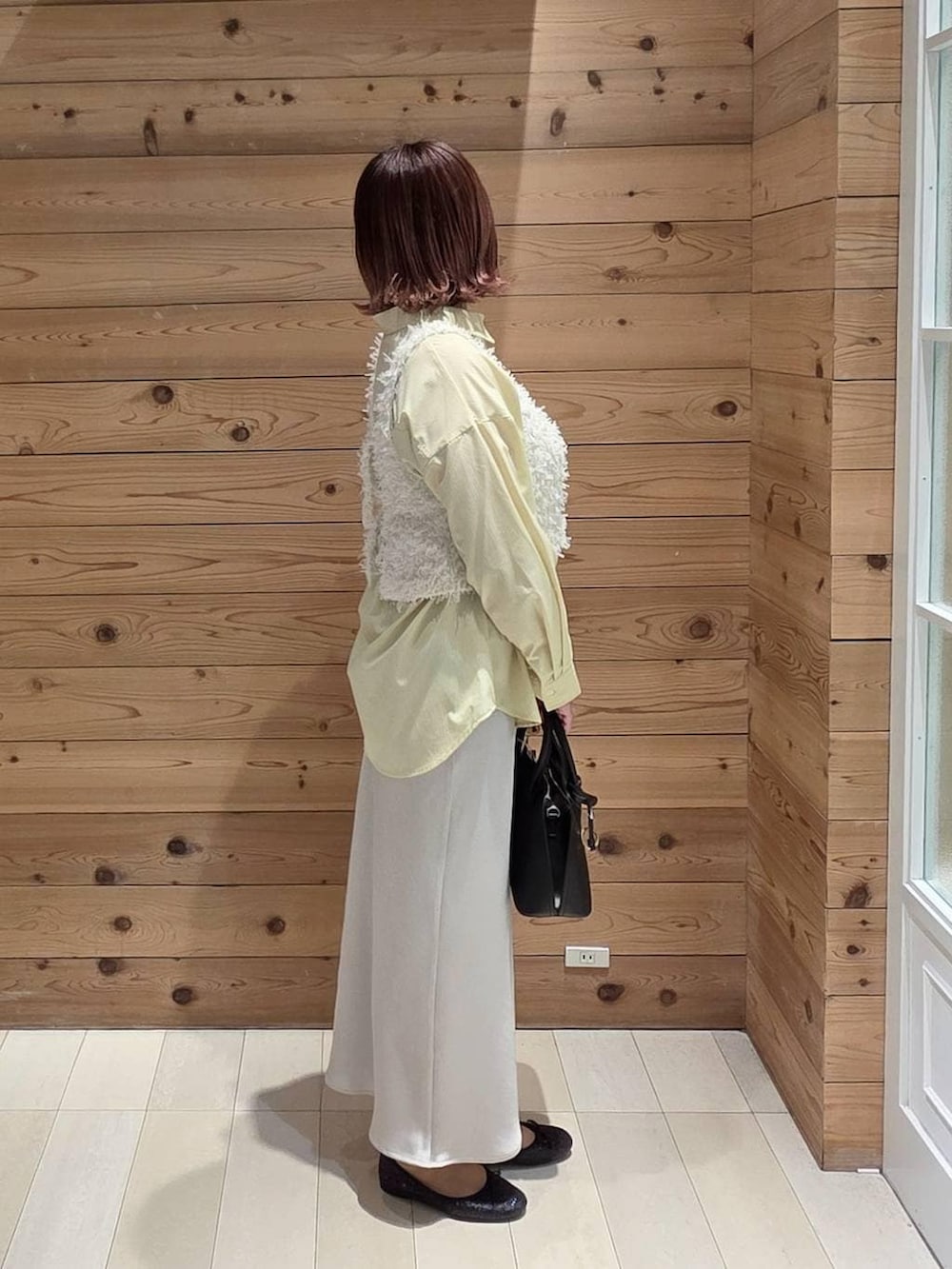 ブラック系のバレエシューズ、ブラック系のショルダーバッグ、イエロー系のシャツ/ブラウスを着用したレディースの春コーディネートの2枚目の写真