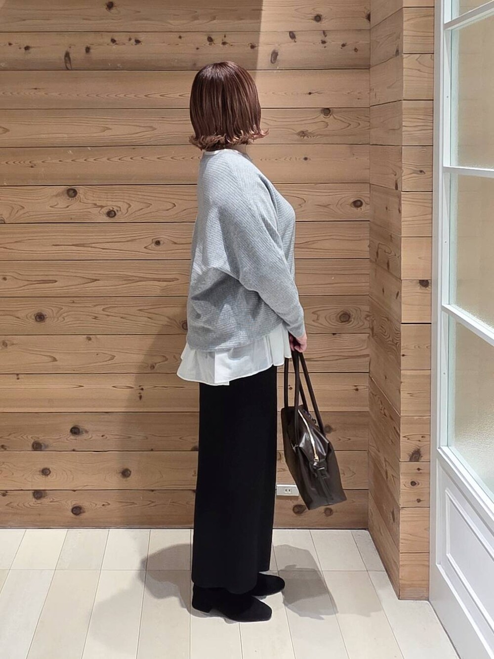 ブルー系のダウンジャケット/コート、ブラウン系のボストンバッグ、ホワイト系のTシャツ/カットソーを着用したレディースの冬コーディネートの2枚目の写真