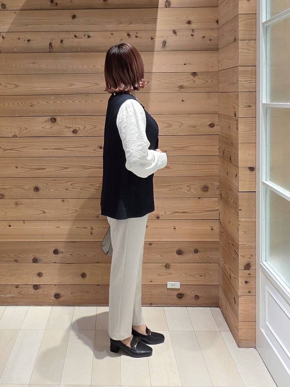 ブラック系のローファー、ホワイト系のショルダーバッグ、ベージュ系のセットアップを着用したレディースの冬コーディネートの2枚目の写真