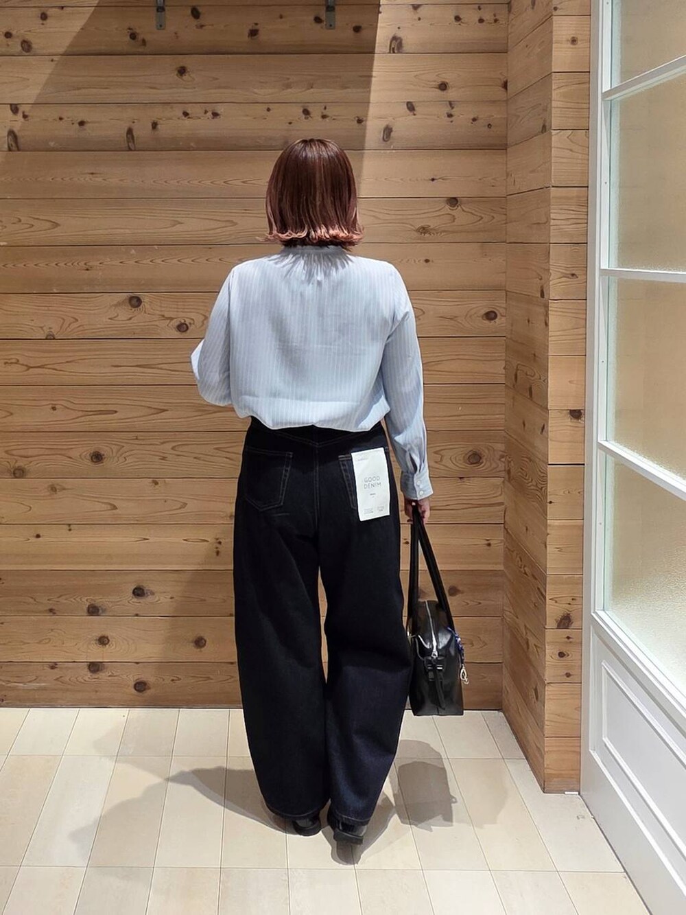 ブラック系のローファー、ブラック系のボストンバッグ、ブルー系のデニムパンツを着用したレディースの春コーディネートの2枚目の写真