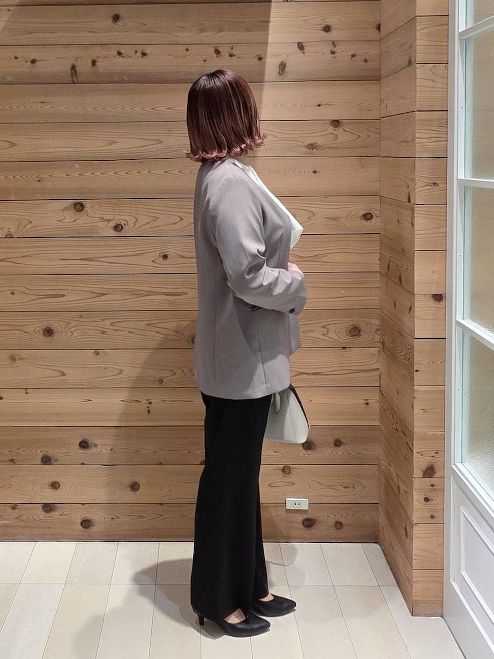 ホワイト系のショルダーバッグ、ブラック系のパンプス、ブラック系のスラックスを着用したレディースの冬コーディネートの2枚目の写真