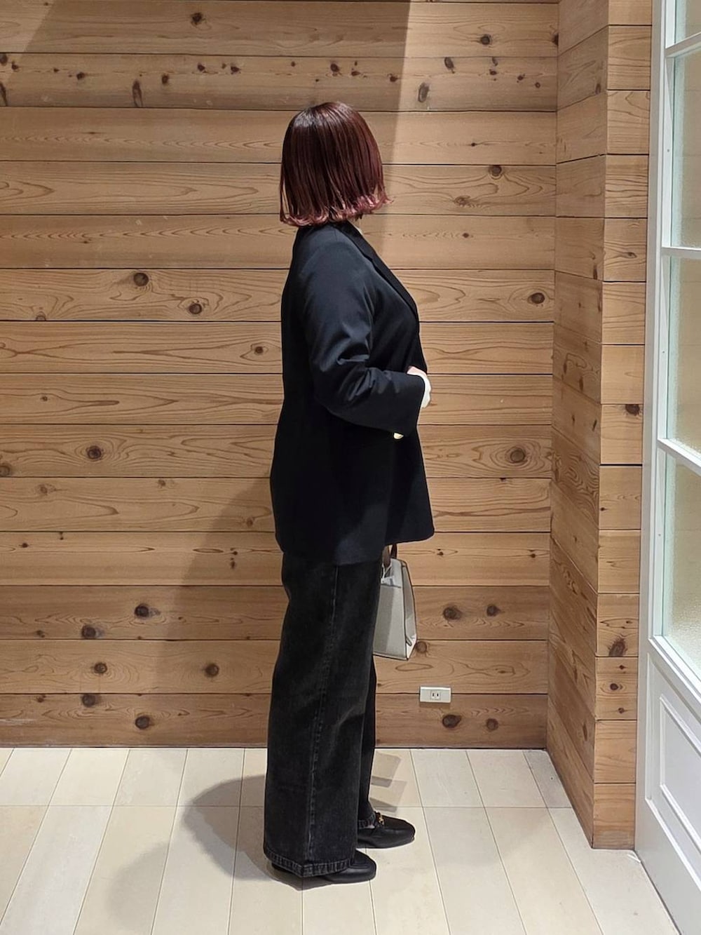 ブラック系のローファー、ホワイト系のショルダーバッグ、ブラック系のデニムパンツを着用したレディースの冬コーディネートの2枚目の写真