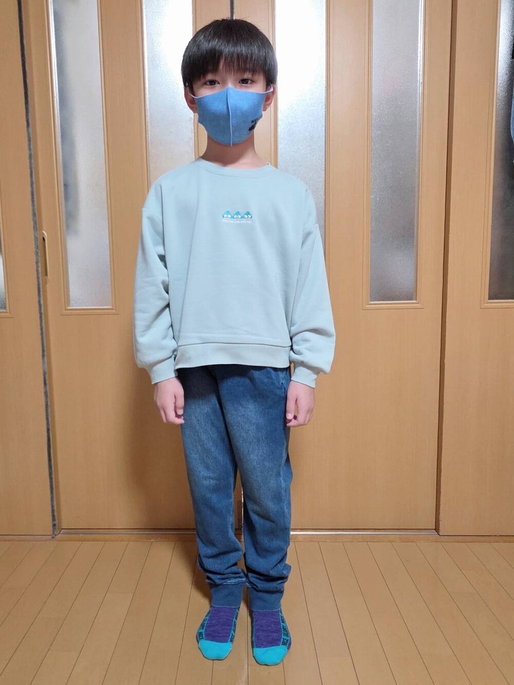 ブルー系のデニムパンツ、ブラック系のブルゾン、グリーン系のスウェットを着用したキッズの秋コーディネートの2枚目の写真