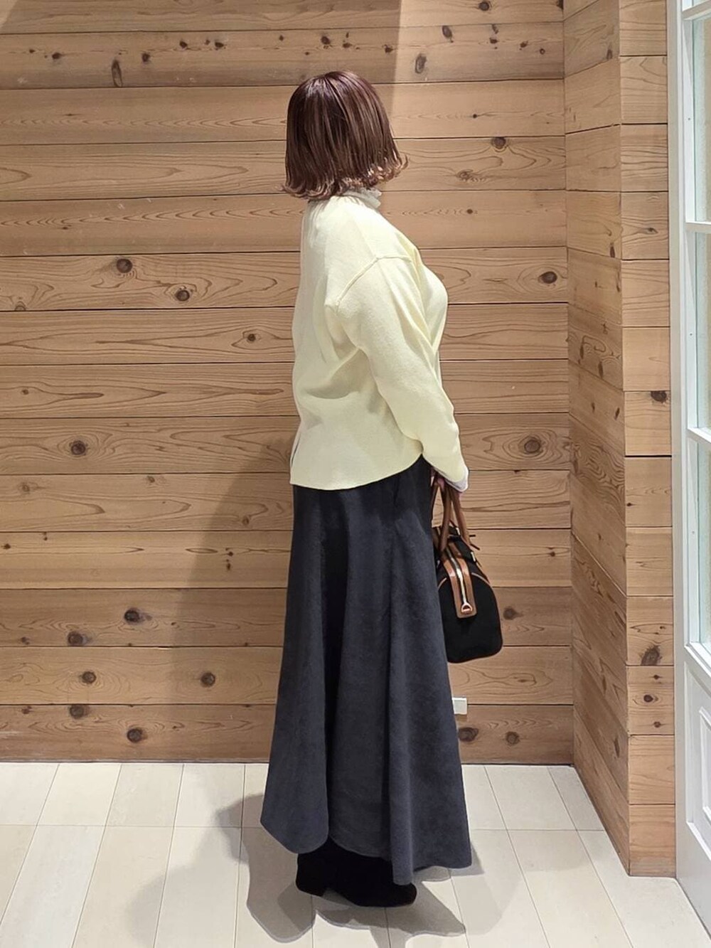 ブラック系のダウンジャケット/コート、グレー系のスカート、ブラック系のボストンバッグを着用したレディースの冬コーディネートの2枚目の写真