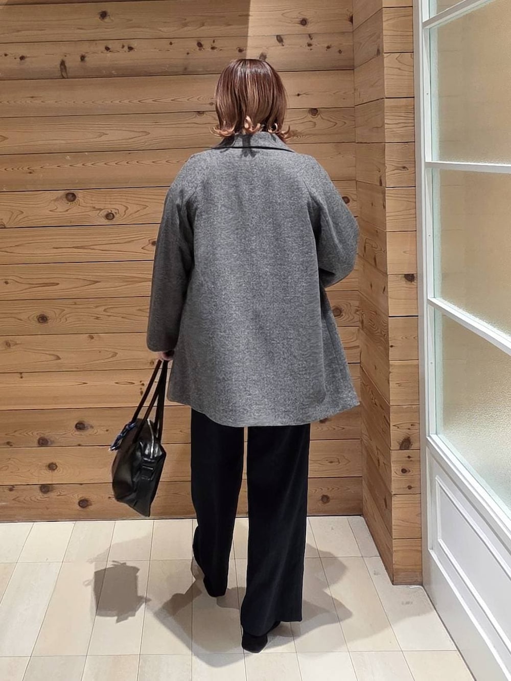 ブラック系のボストンバッグ、グレー系のチェスターコート、ブラック系のその他パンツを着用したレディースの冬コーディネートの3枚目の写真