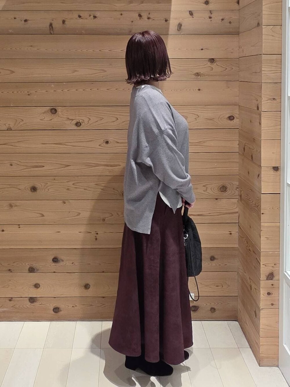 ブラウン系のチェスターコート、レッド系のスカート、ブラック系のハンドバッグを着用したレディースの冬コーディネートの2枚目の写真