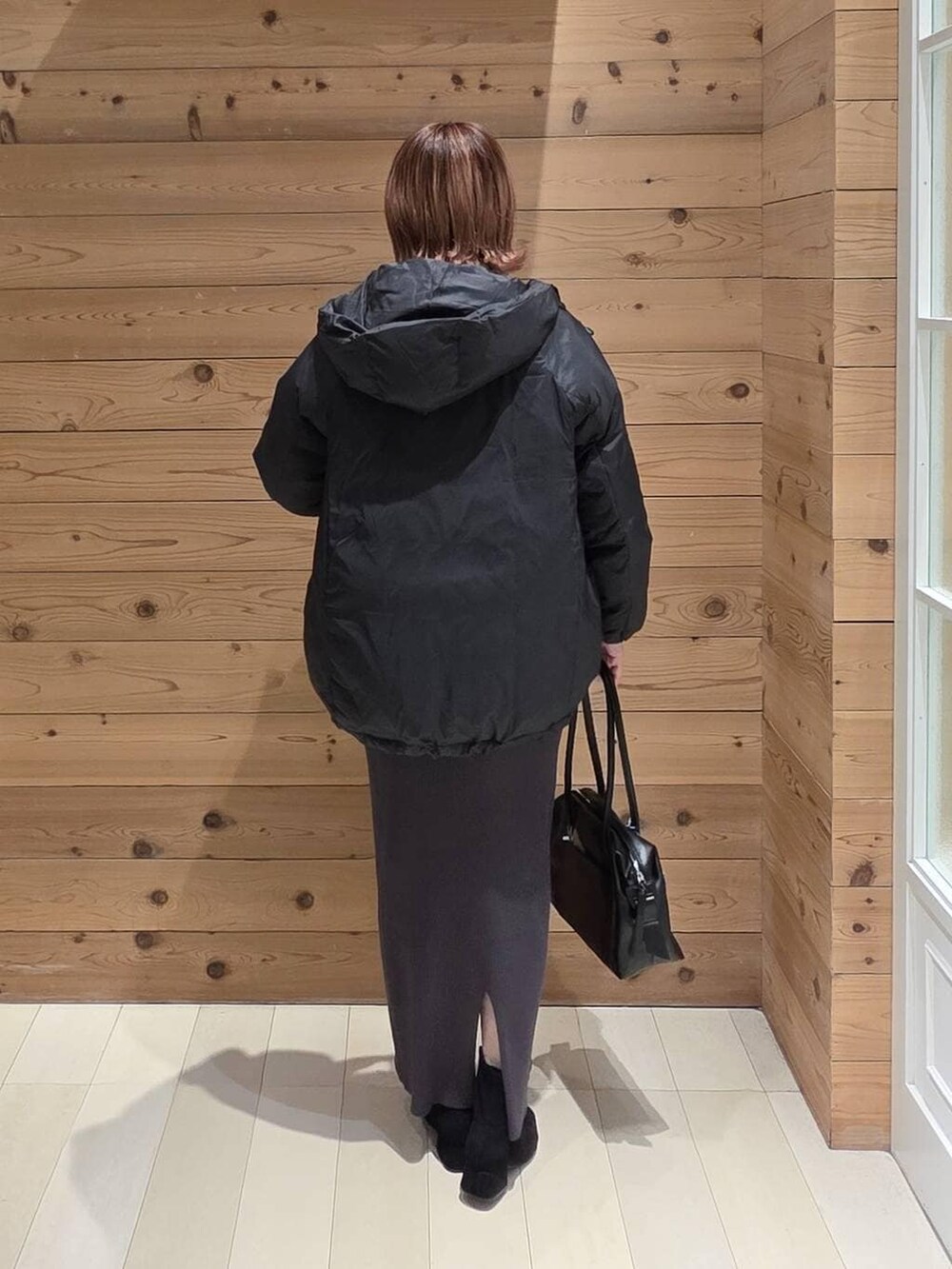 ブラック系のダウンジャケット/コート、ブラック系のボストンバッグ、ホワイト系のシャツ/ブラウスを着用したレディースの秋コーディネートの3枚目の写真