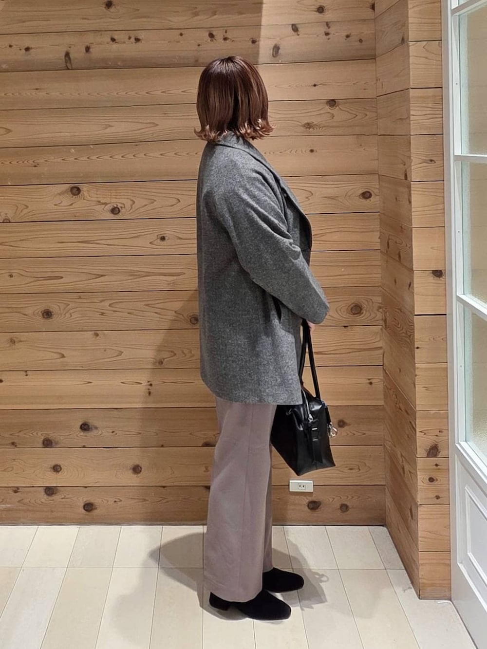 ブラック系のボストンバッグ、グレー系のチェスターコート、レッド系のニット/セーターを着用したレディースの冬コーディネートの2枚目の写真