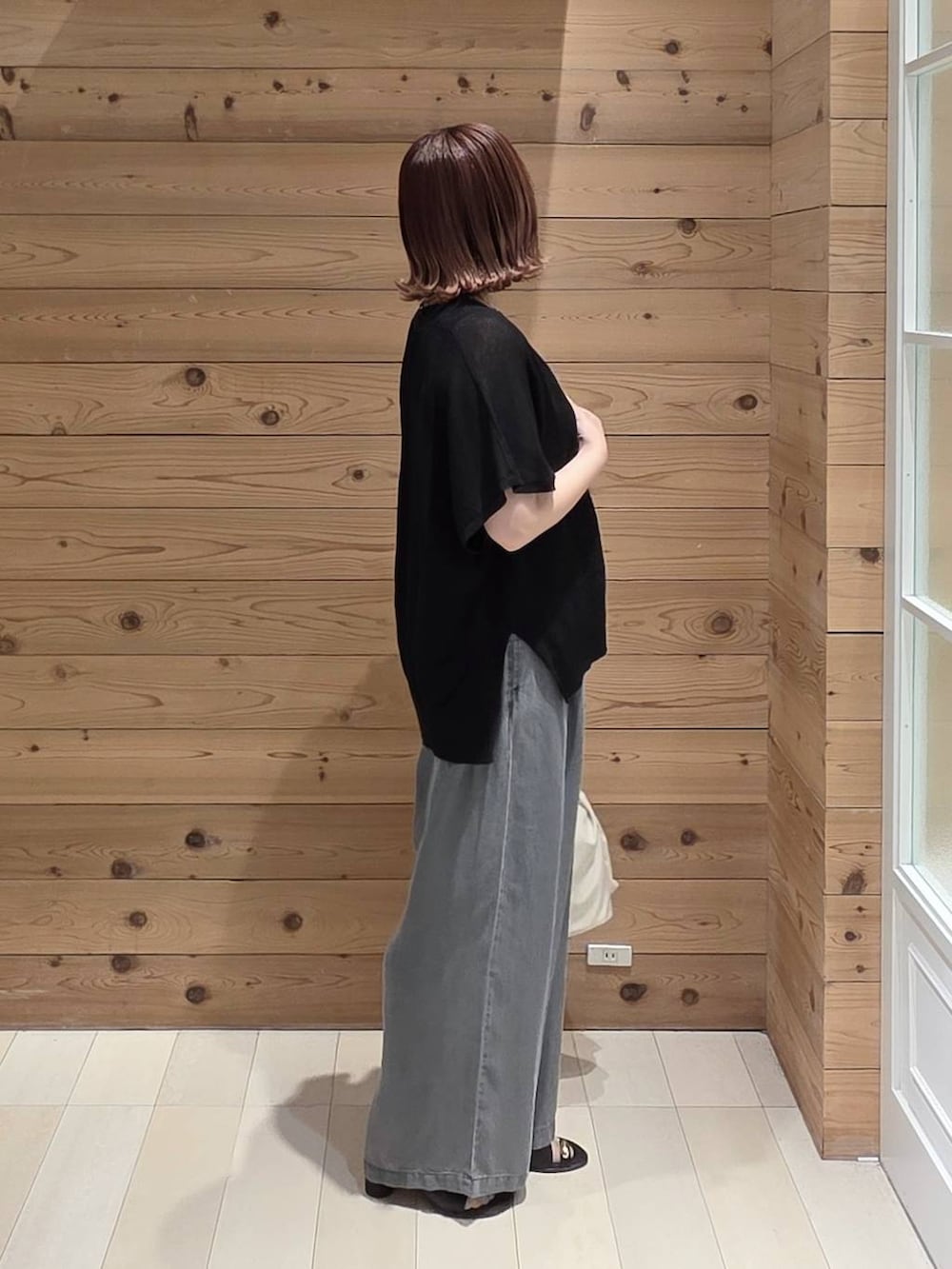 ホワイト系のショルダーバッグ、ブラック系のタンクトップ、ブラック系のデニムパンツを着用したレディースの春コーディネートの2枚目の写真