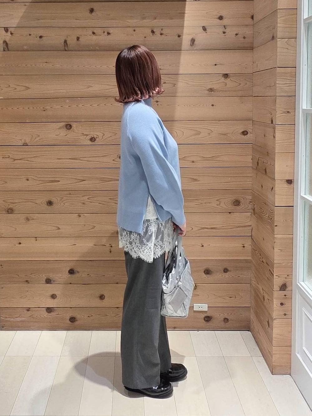 ブラック系のローファー、シルバー系のトートバッグ、グレー系のスラックスを着用したレディースの冬コーディネートの2枚目の写真