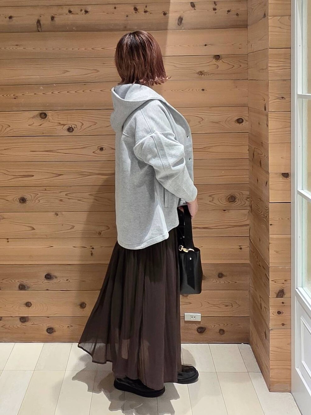 ブラック系のローファー、ブラック系のショルダーバッグ、ブラウン系のスカートを着用したレディースの秋コーディネートの2枚目の写真