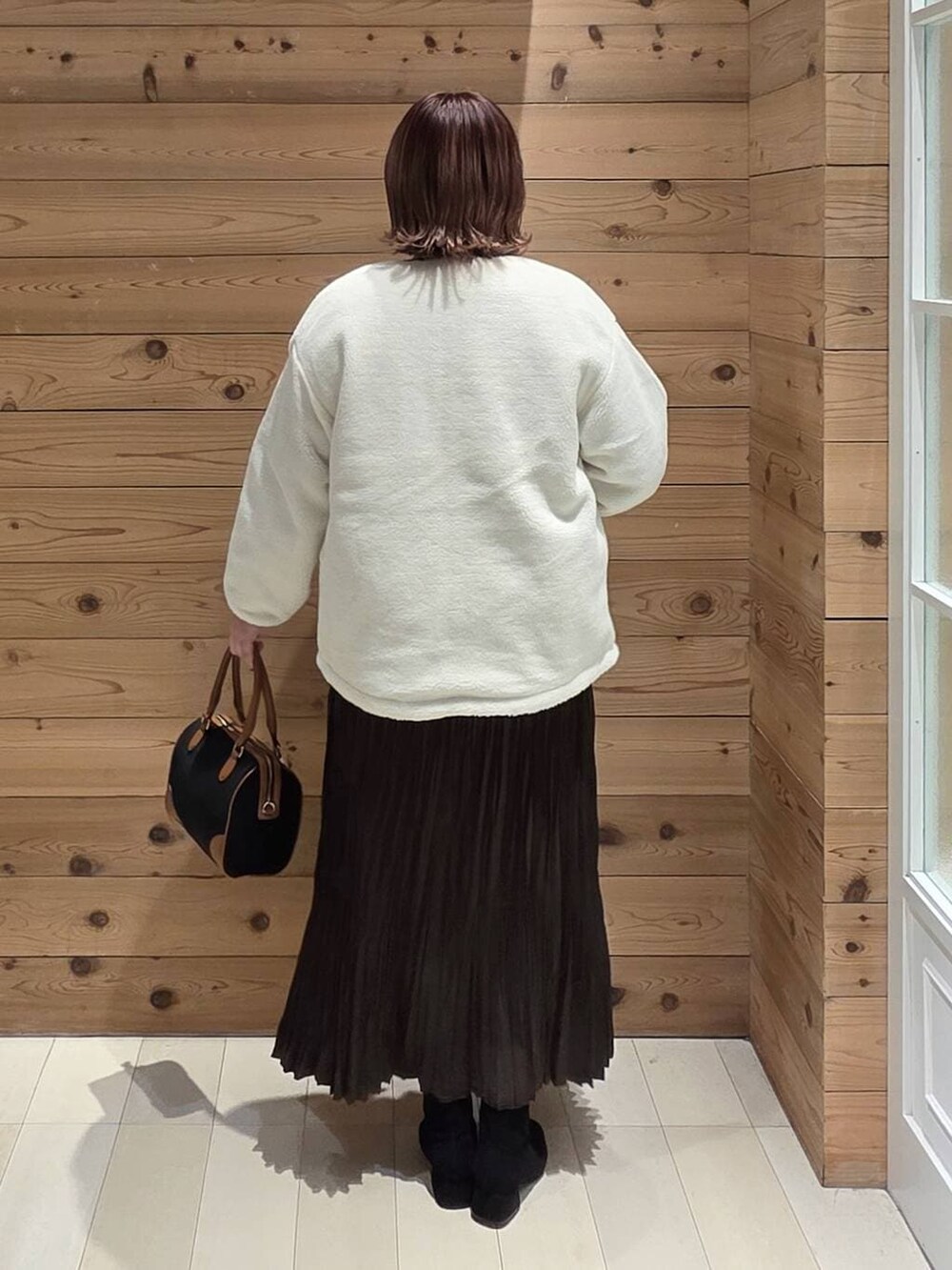 ホワイト系のブルゾン、ブラック系のボストンバッグ、グレー系のブーツを着用したレディースの冬コーディネートの3枚目の写真