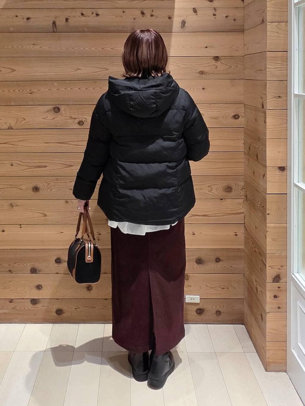 ブラック系のダウンジャケット/コート、レッド系のスカート、ブラック系のブーツを着用したレディースの冬コーディネートの3枚目の写真