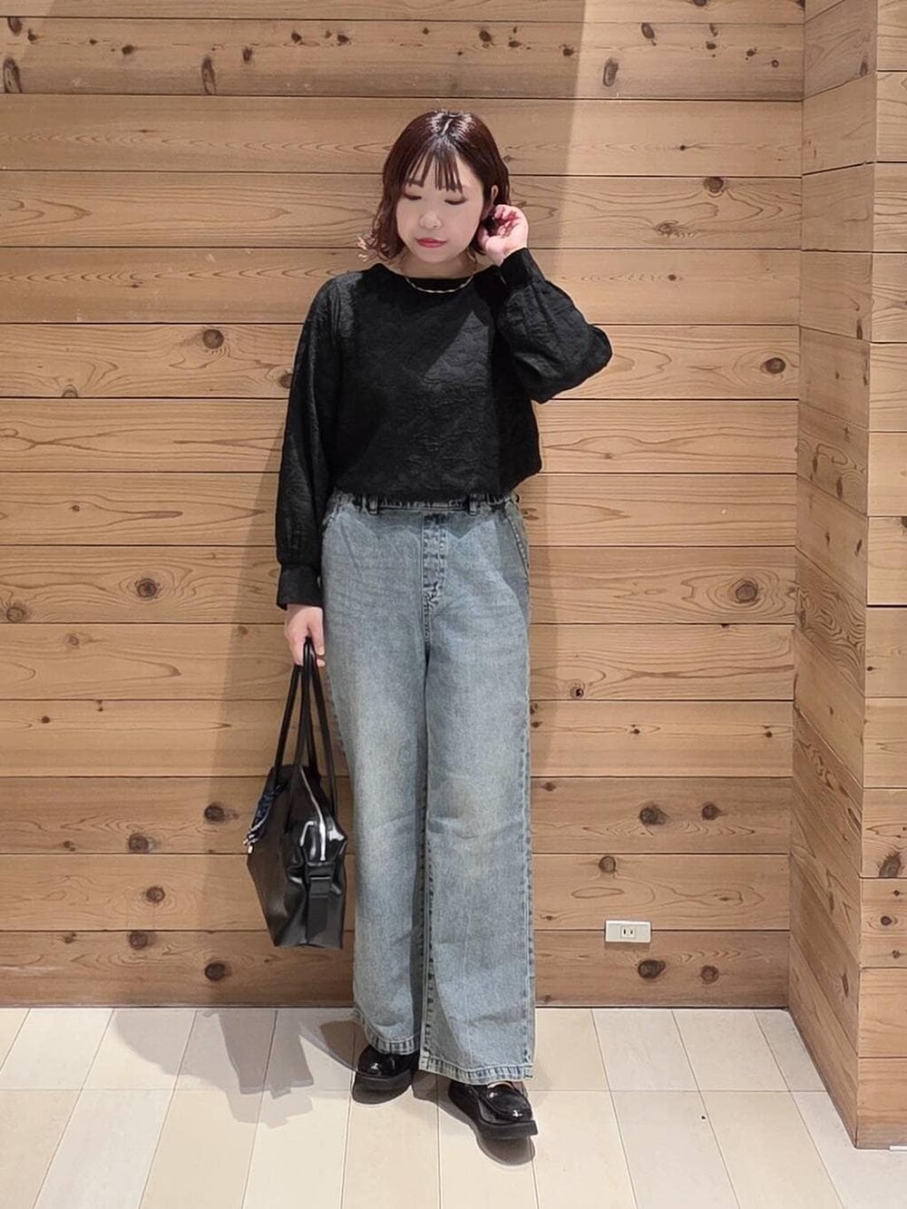 ブラック系のローファー、ブラック系のボストンバッグ、ブルー系のデニムパンツを着用したレディースの冬コーディネートの4枚目の写真