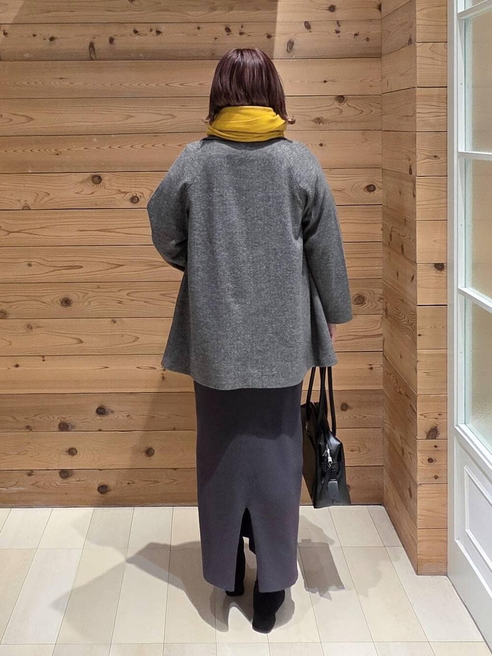 ブラック系のボストンバッグ、グレー系のチェスターコート、グレー系のワンピースを着用したレディースの冬コーディネートの3枚目の写真