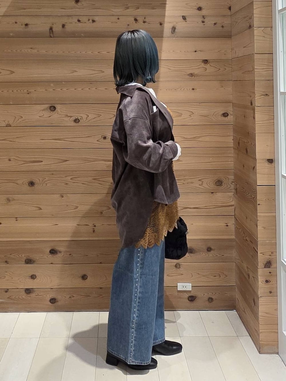 ブルー系のデニムパンツ、オレンジ系のキャミソール、ブラック系のブーツを着用したレディースの秋コーディネートの2枚目の写真