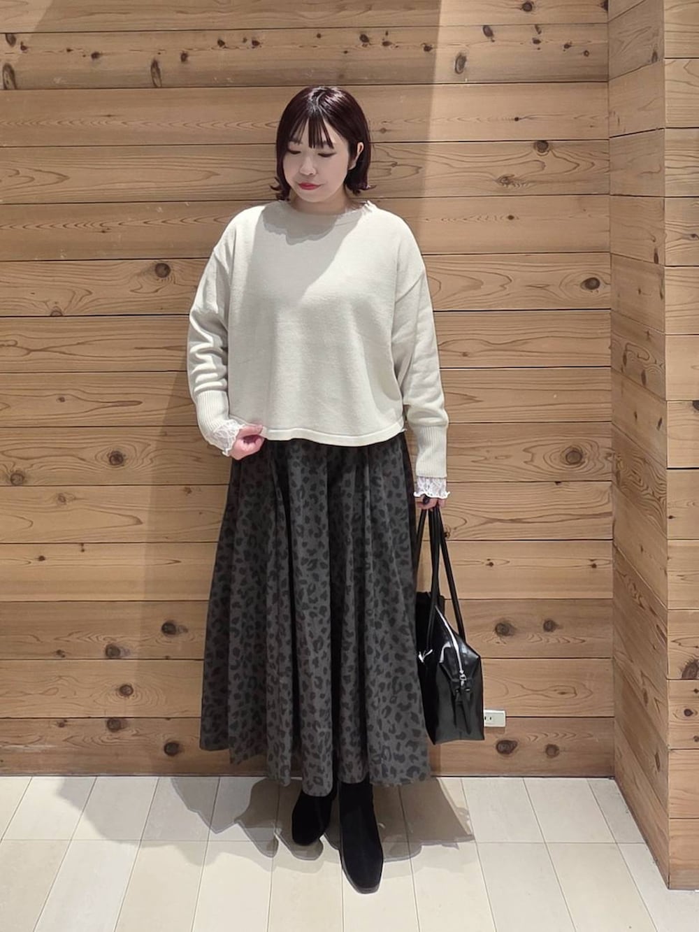 ホワイト系のマウンテンパーカー、ベージュ系のニット/セーター、ブラック系のボストンバッグを着用したレディースの冬コーディネートの4枚目の写真