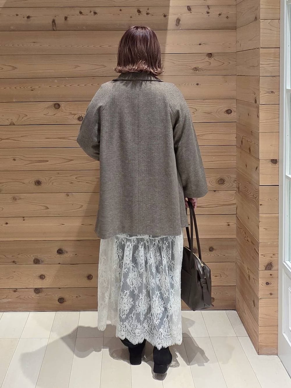 ブラウン系のボストンバッグ、ブルー系のデニムパンツ、ブラウン系のチェスターコートを着用したレディースの冬コーディネートの3枚目の写真