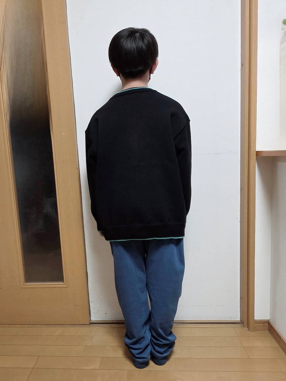 ブラック系のTシャツ/カットソー、ブルー系のデニムパンツ、ブラック系のニット/セーターを着用したキッズの冬コーディネートの3枚目の写真