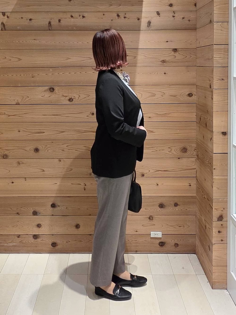 ブラック系のローファー、ブラック系のショルダーバッグ、ブラウン系のスラックスを着用したレディースの冬コーディネートの2枚目の写真